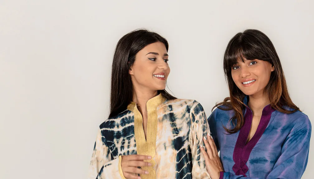 Two women wearing colorful handmade Moroccan caftan dresses